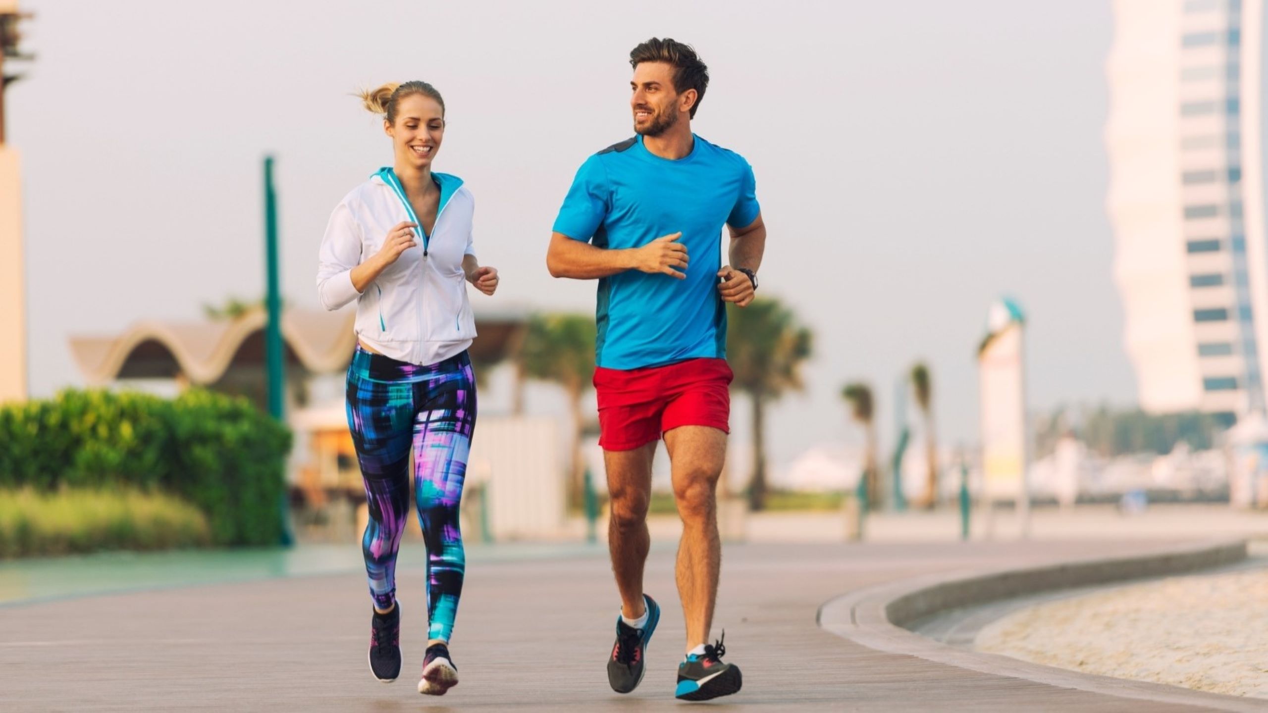 Man and woman running on path near Burj Al Arab outdoor fitness training temperature parks morning