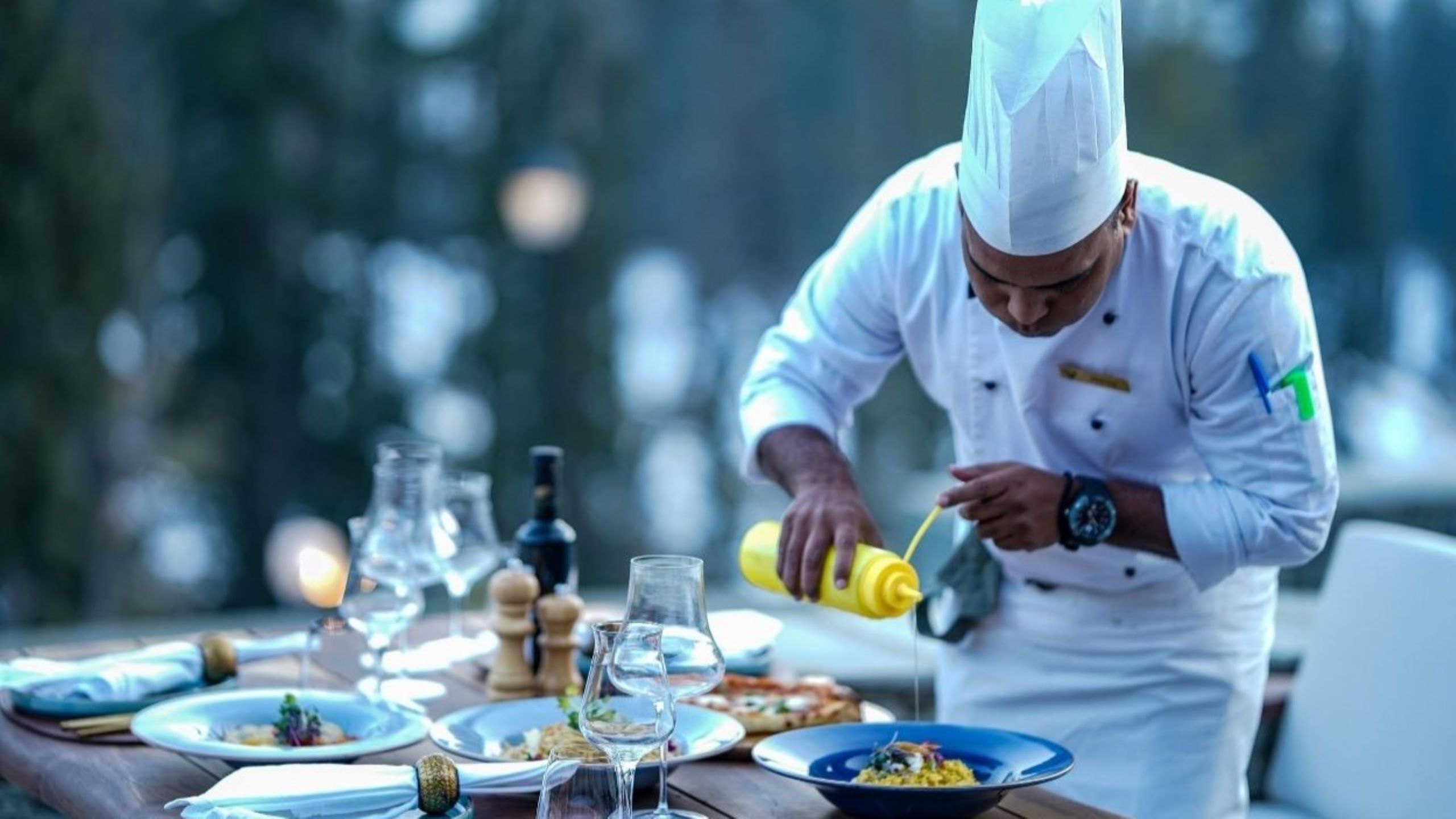 Renowned celebrity chef plating exquisite fine dining dish at Michelin-starred restaurant in Dubai, representing culinary legends creating signature cuisine for world-class dining experiences