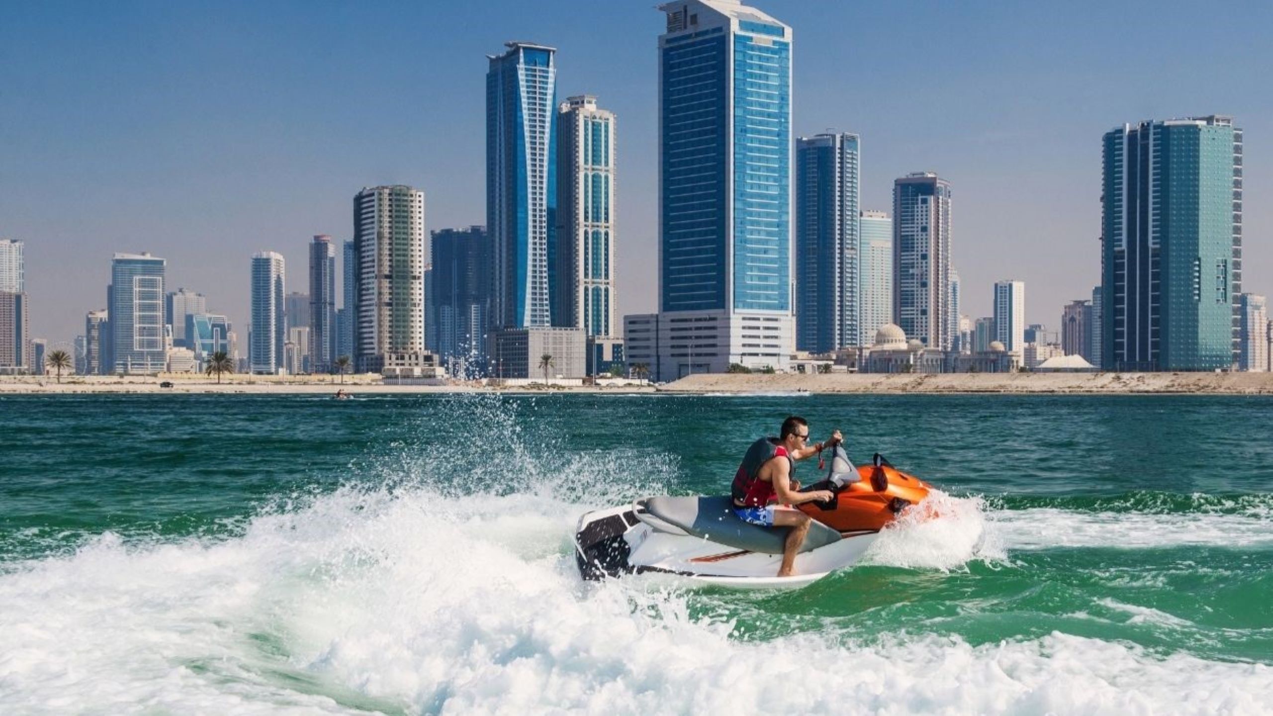 People enjoying jet skiing beach sports at JBR Dubai with Marina skyline background, showcasing popular water activities along Arabian Gulf coastline offering adrenaline and scenic views