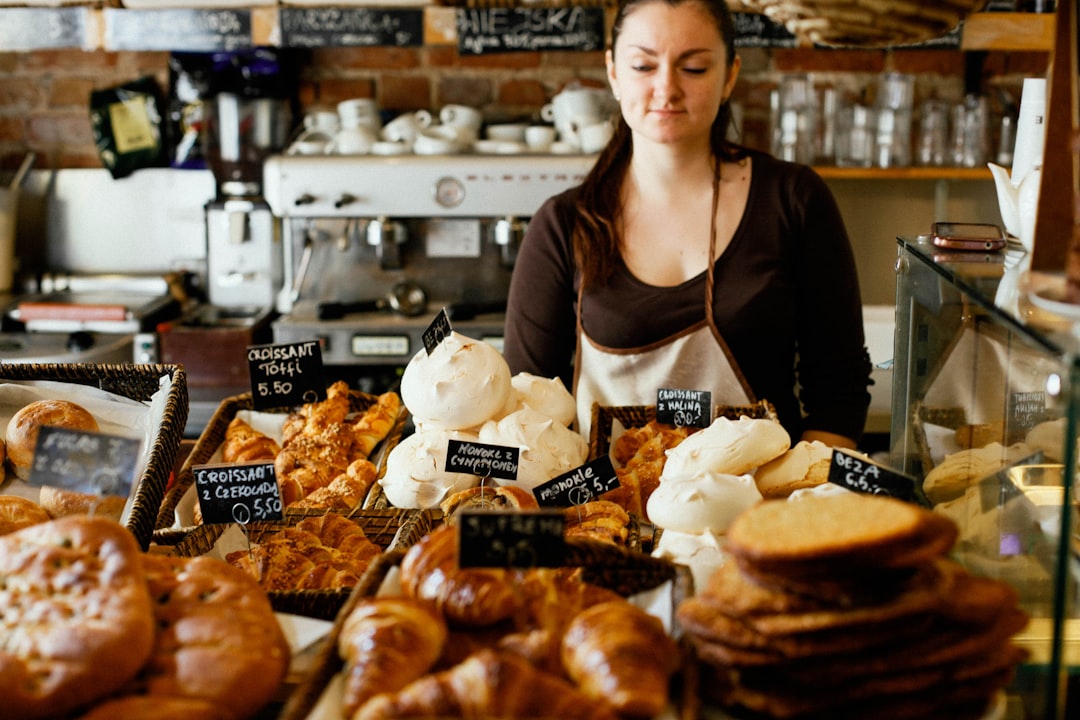 A smiling woman selecting a treat at one of Dubai's gluten-free bakeries, surrounded by fresh baked goods on a cafe counter.