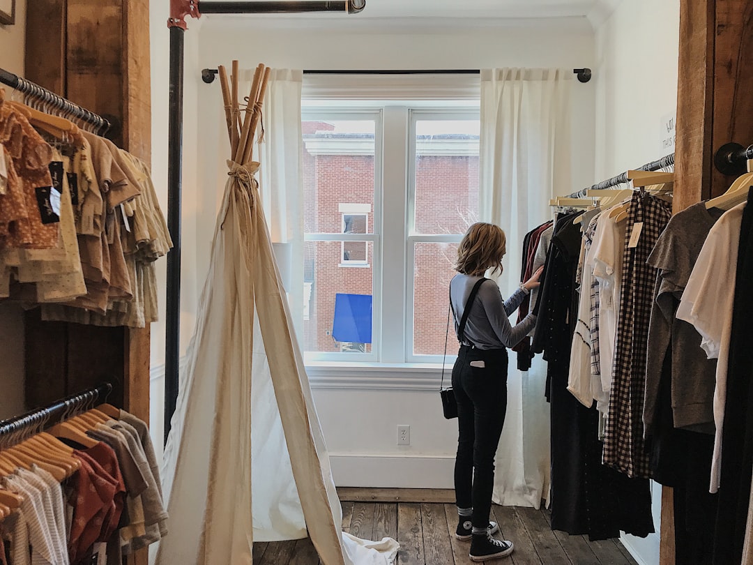 A woman browses slow fashion garments at an ethical boutique in Dubai, examining fabric quality with care.