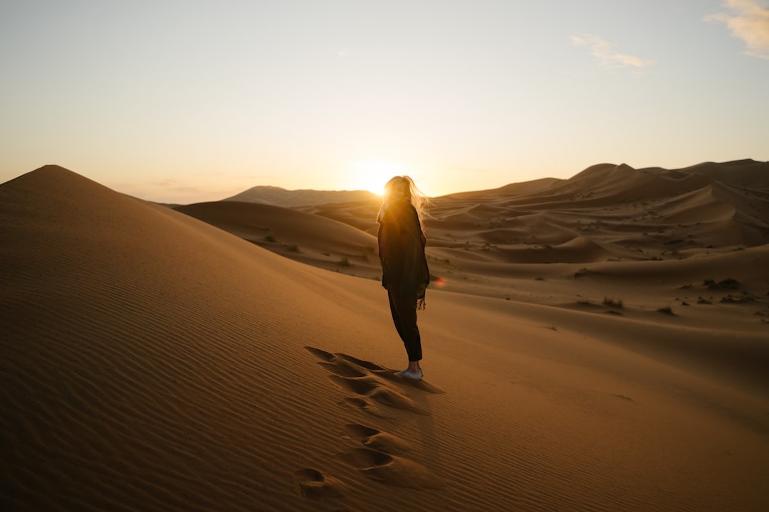 A traveller watching the sunrise over golden dunes during a summer desert escape near Dubai