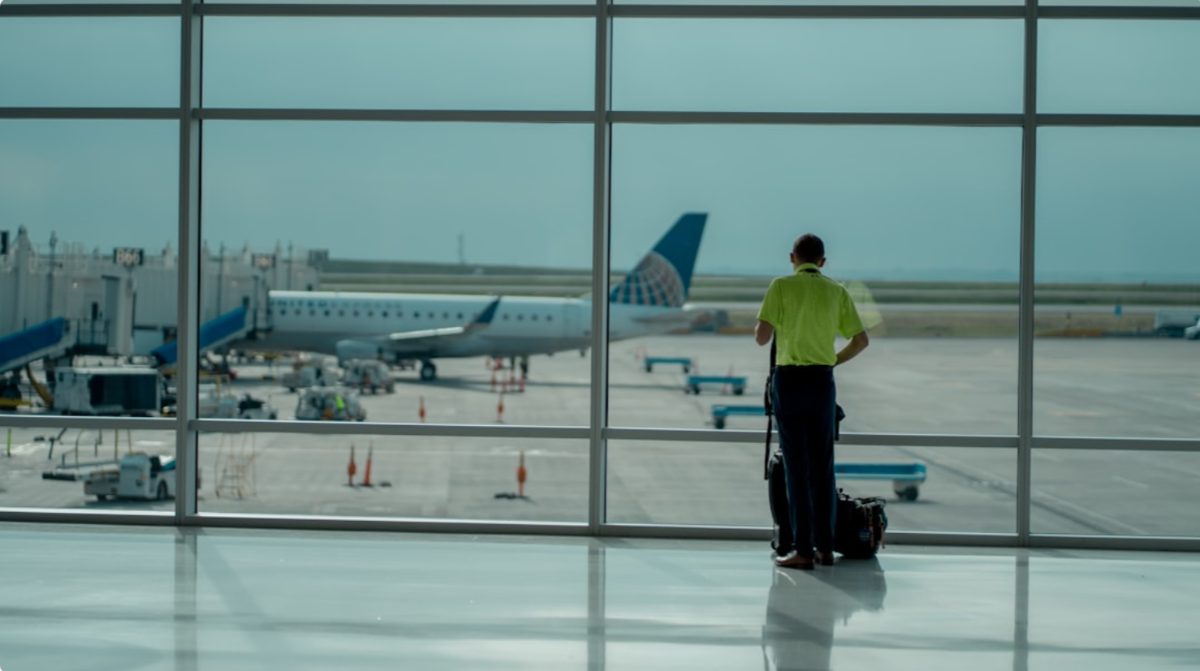 A traveler checking the departures board at Dubai International Airport before choosing summer flights to Europe