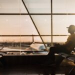 A traveler at Dubai International Airport checking long-haul fares on a smartphone before booking a summer flight