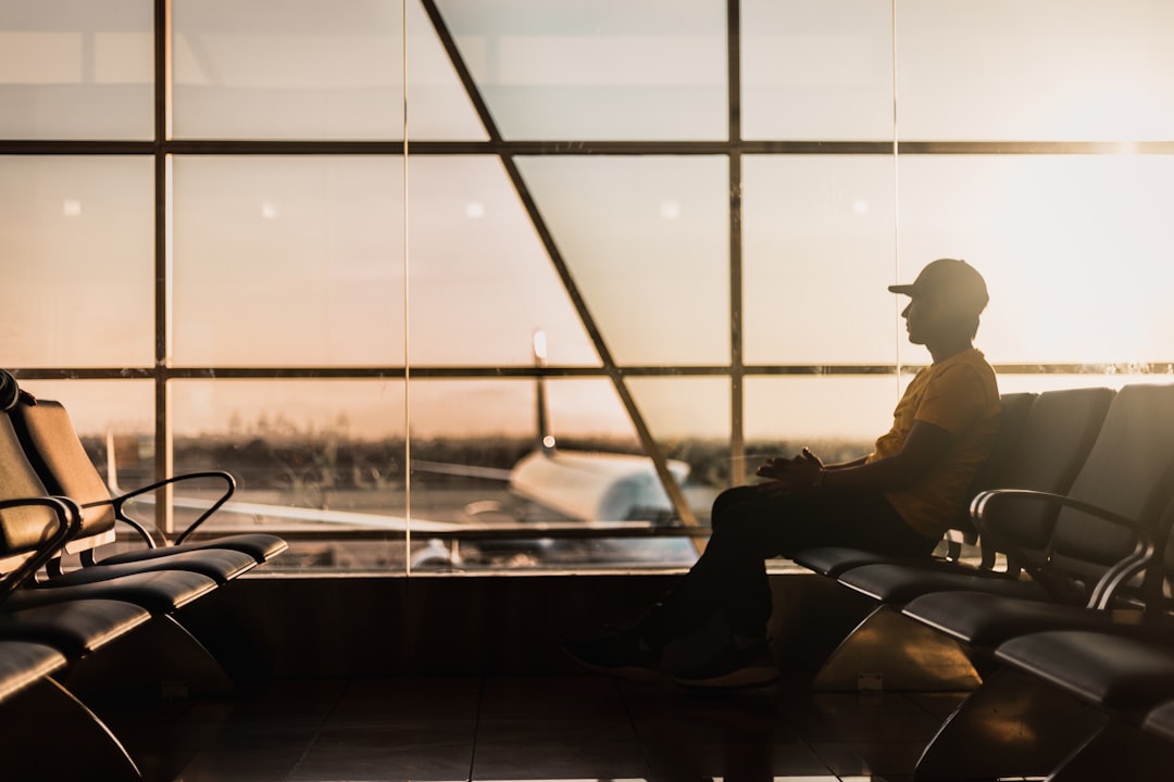 A traveler at Dubai International Airport checking long-haul fares on a smartphone before booking a summer flight