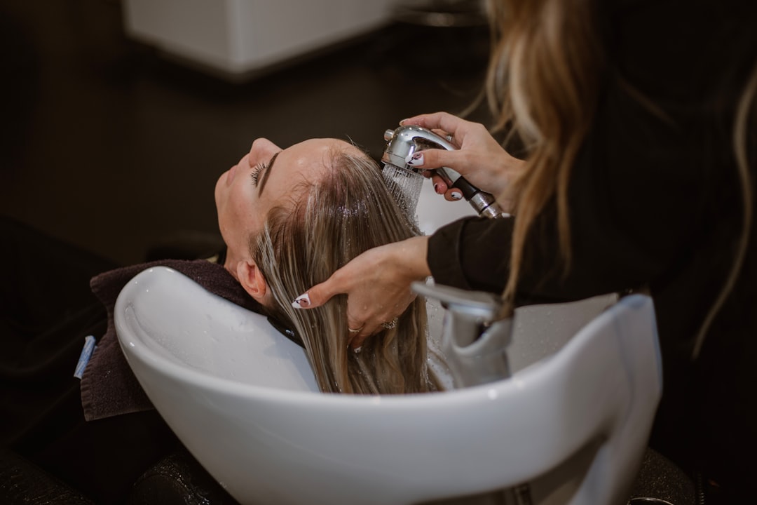 A stylist applying professional hair treatments to a client's hair in a Dubai salon, protecting against humidity and frizz.