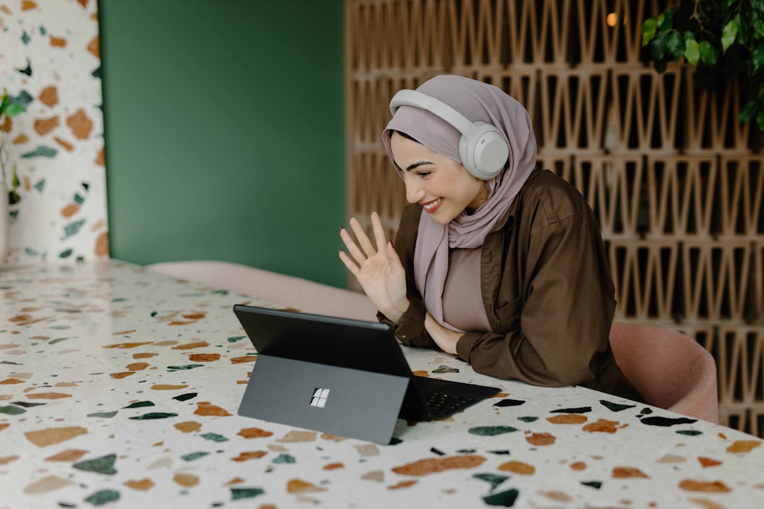 A digital nomad working at a bright coworking space in Dubai, with a laptop open and city views behind her