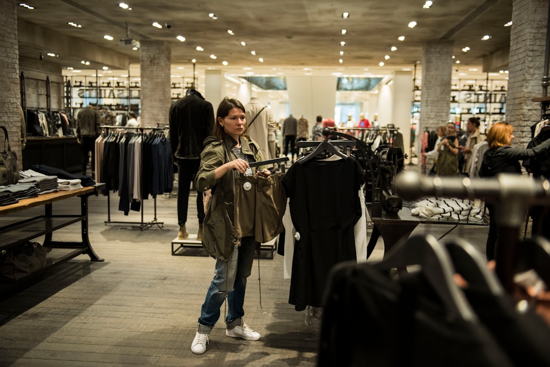 A woman browsing clothing rails at a preloved boutique, building a sustainable wardrobe in Dubai on a mid-range budget.