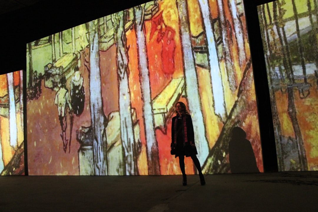 A woman walks through a glowing digital projection room at an immersive art experience inside a Dubai mall
