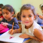 A mother helped her young child pack a school bag at home, preparing for the new school term in Dubai