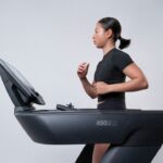 A woman focused on her indoor training session on a treadmill inside a modern Dubai gym, preparing for an autumn race