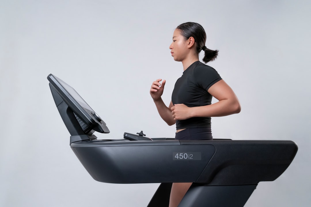 A woman focused on her indoor training session on a treadmill inside a modern Dubai gym, preparing for an autumn race
