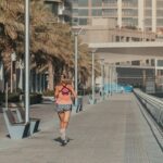 A woman stretching on a shaded outdoor path as part of her morning routine in Dubai's early hours
