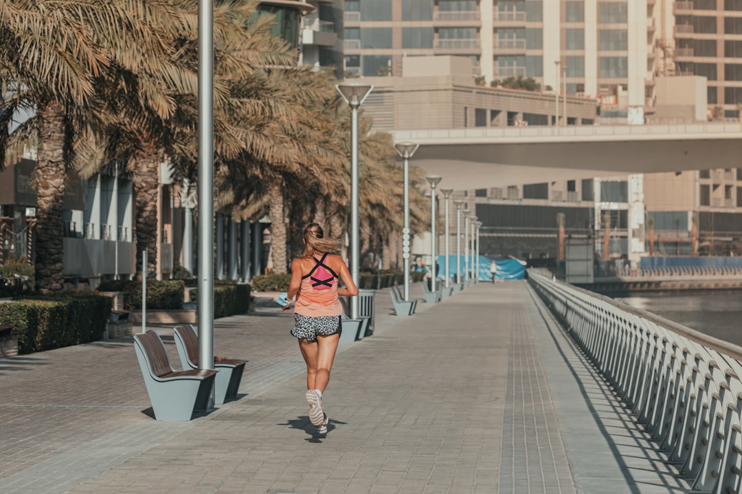 A woman stretching on a shaded outdoor path as part of her morning routine in Dubai's early hours