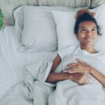 A woman opening curtains to morning sunlight as part of her sleep schedule reset in Dubai