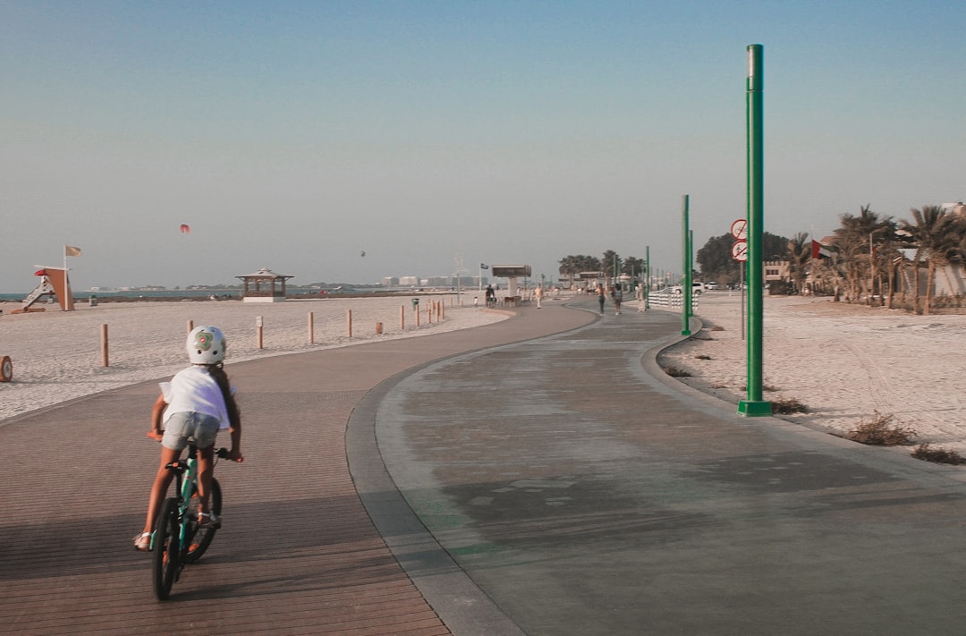 A family cycling along a beachside track in Dubai, enjoying outdoor activities together in the early morning light