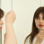 A woman applying rich moisturiser in a bright bathroom as part of her Dubai skincare routine for autumn