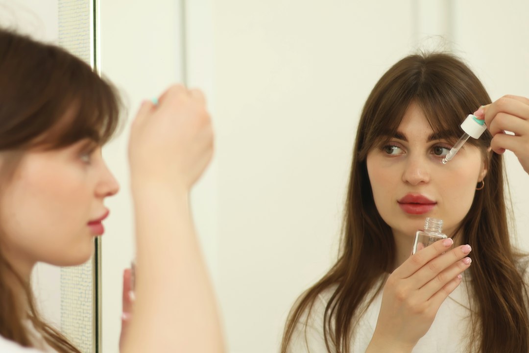 A woman applying rich moisturiser in a bright bathroom as part of her Dubai skincare routine for autumn