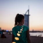 A woman dressed for an evening out stands in front of Dubai Opera, ready to enjoy the Dubai cultural calendar this autumn