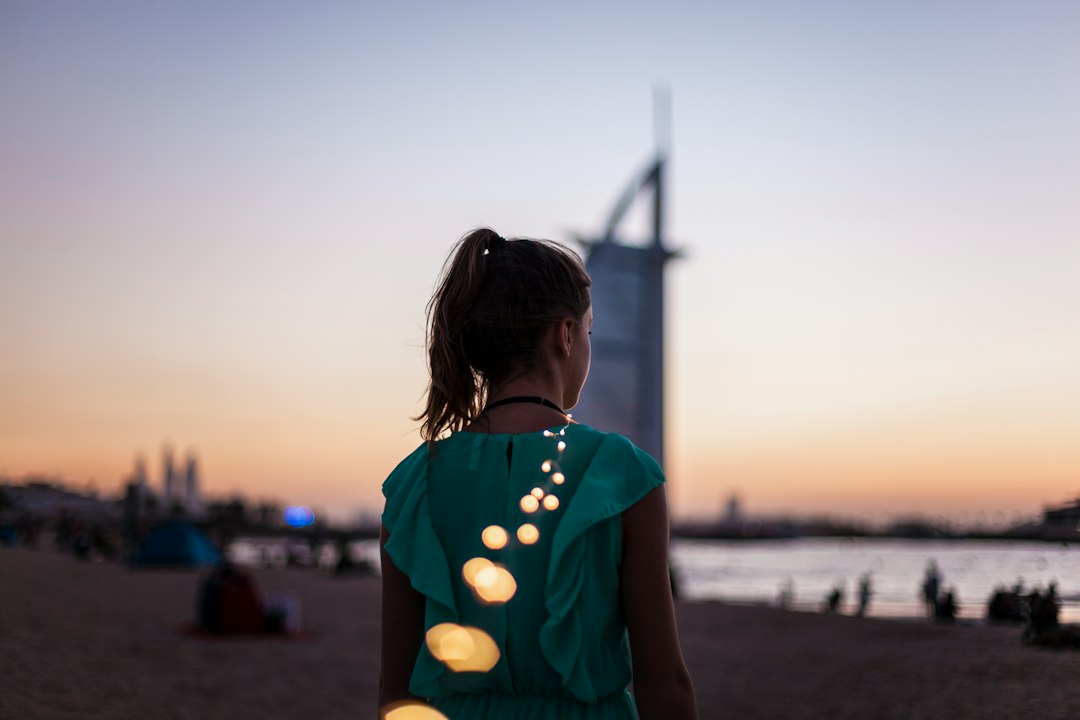A woman dressed for an evening out stands in front of Dubai Opera, ready to enjoy the Dubai cultural calendar this autumn